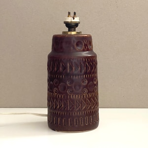May include: A brown ceramic table lamp with a geometric pattern. The lamp has a brass base and a white ceramic socket.