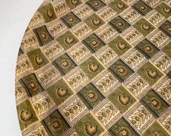Puede incluir: Una bandeja redonda con un patrón de cuadros en tonos verdes y beige. El patrón presenta un diseño floral repetitivo.