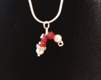 May include: A silver chain necklace with a red and white beaded pendant shaped like a Santa hat.