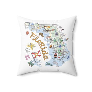 May include: A square white throw pillow featuring a colorful illustrated map of Florida. The design includes the text Florida and The Sunshine State, along with drawings of local landmarks, wildlife, the state flag, palm trees, and beach items.