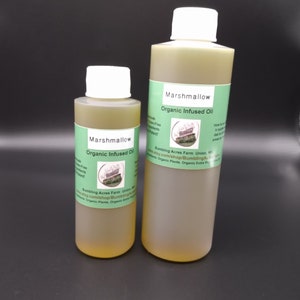 Peut inclure: Deux bouteilles en verre d'huile infusée à la guimauve biologique. Les bouteilles sont étiquetées avec le texte "Marshmallow Organic Infused Oil" et l'adresse du site Web "etsy.com/shop/BumblingAcres".