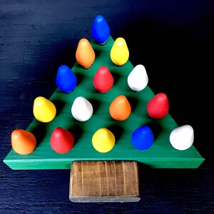 May include: A wooden Christmas tree decoration with a green base and colorful bulb-shaped ornaments. The ornaments are in shades of blue, orange, red, yellow, and white. The tree has a rectangular wooden base.