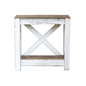 May include: White farmhouse style end table with a distressed wood finish and a lower shelf. The table has a simple X-shaped design on the front.
