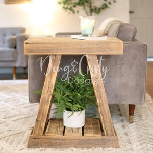 May include: A rustic wooden side table with a triangular base and a rectangular top. The table features a lower shelf and holds a potted plant. The table is approximately 24 inches tall.