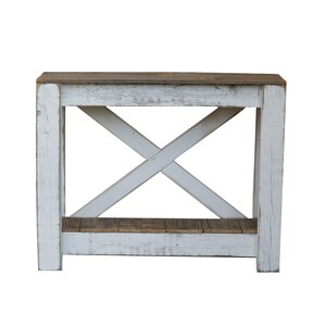 May include: Whitewashed wooden console table with a distressed finish. The table has a single shelf and an X-shaped support structure.