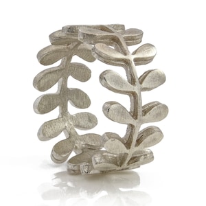May include: A silver ring featuring a delicate design of leaves. The ring is crafted from smooth, brushed metal and has a simple, elegant appearance.