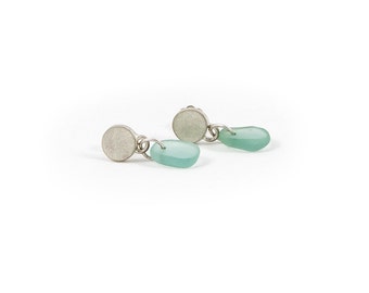May include: A pair of silver earrings with a round silver charm and a light blue teardrop-shaped charm.