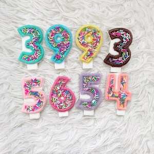 May include: Set of eight colorful candles shaped like numbers 3, 9, 3, 5, 6, 5, 4, decorated with colorful sprinkles.