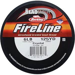 May include: A spool of black FireLine Crystal braided fishing line by Berkley. The spool is labeled with the brand name, line type, and specifications: 6lb, 0.006in avg. dia, 125yd, 1392825, FLFSH6-CY. The spool is made in the USA.