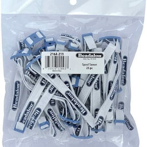 Könnte beinhalten: Ein durchsichtiger Plastikbeutel mit 25 Beadalon Spool Tamer Gummibändern. Jedes weiße Gummiband ist mit dem blauen Beadalon-Logo versehen und an einem hellblauen Kunststoffclip befestigt. Ein weißes Etikett auf dem Beutel zeigt 216A-211, Beadalon, Spool Tamer, 25 pc und einen Strichcode.