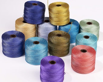 May include: Assortment of spools of colorful embroidery floss in shades of blue, green, gold, purple, and red. The spools are arranged in a pyramid shape on a white surface.