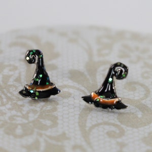 May include: A pair of black witch hat stud earrings with orange and green glitter accents.