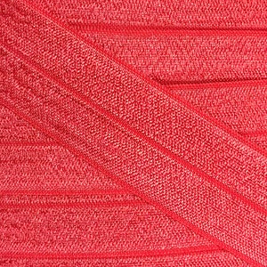 K&ouml;nnte beinhalten: Roter elastischer Stoff mit einer strukturierten, gerippten Oberfl&auml;che. Der Stoff ist in der Mitte gefaltet und erzeugt ein diagonales Muster.