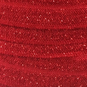 May include: Red glitter fabric with a textured, woven pattern. The fabric is folded in a series of overlapping layers.
