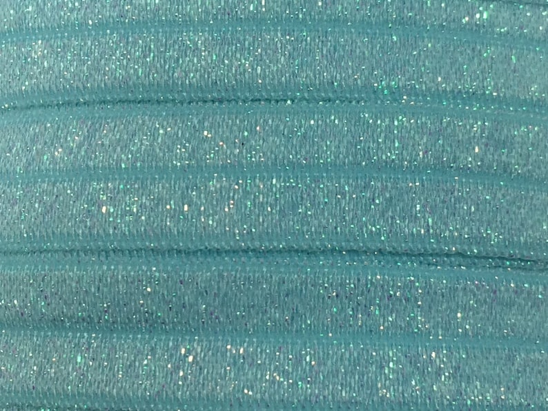 Pode incluir: Close-up de uma banda el&aacute;stica azul claro com acabamento brilhante. A banda &eacute; feita de um material macio e el&aacute;stico e tem um brilho sutil.