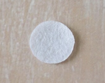 May include: A white round cotton pad, commonly used for makeup removal or skincare.