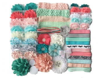 May include: A set of 18 headbands for babies and toddlers. The set includes a variety of colors, patterns, and textures, including coral, mint green, white, and gray. The headbands are made of elastic and are adorned with fabric flowers and bows.