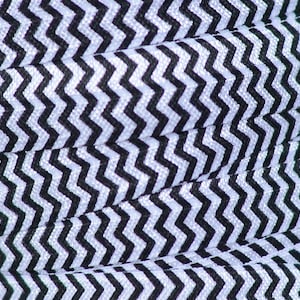 Op de afbeelding: Zwart-wit geblokt elastisch met een zigzagpatroon. Het elastisch is gevouwen en toont het patroon dat zich herhaalt.