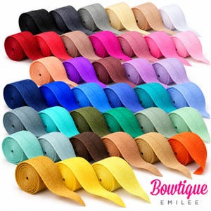 May include: A collection of fabric elastic fold-over ribbon rolls in a wide spectrum of colors including black, gray, white, red, pink, purple, blue, green, orange, and yellow. The text Bowtique EMILEE is printed in pink and black at the bottom.
