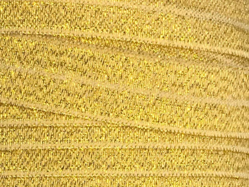 Puede incluir: Adorno el&aacute;stico dorado con un acabado brillante. El adorno est&aacute; hecho de un material suave y el&aacute;stico y tiene una textura acanalada sutil.