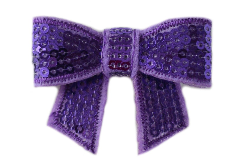 Puede incluir: Un lazo morado con lentejuelas. El lazo est&aacute; hecho de terciopelo y tiene un acabado brillante.