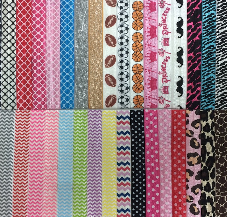 Op de afbeelding: Een verzameling kleurrijke haarbandjes met verschillende patronen, waaronder geometrische, dierenprint en sportthema's. De haarbandjes zijn in twee rijen gerangschikt.