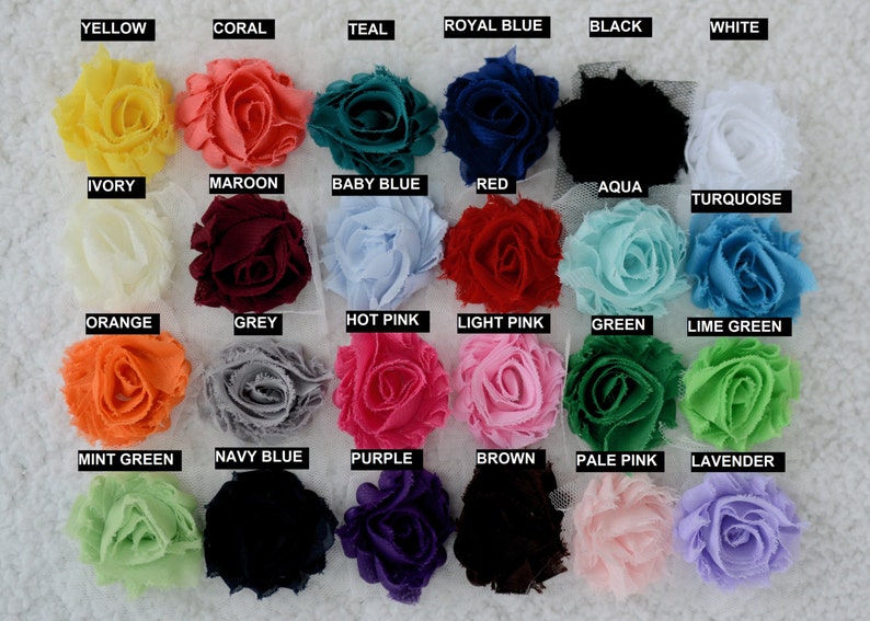 May include: A color chart of 24 fabric flower embellishments. The flowers are arranged in four rows of six flowers each. The flowers are in a variety of colors, including yellow, coral, teal, royal blue, black, white, ivory, maroon, baby blue, red, aqua, turquoise, orange, grey, hot pink, light pink, green, lime green, mint green, navy blue, purple, brown, pale pink, and lavender.