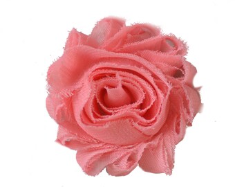 May include: A coral pink fabric flower with a ruffled texture.