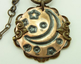 May include: A copper and brass necklace with a pendant featuring a crescent moon and stars design. The pendant is attached to a chain with a clasp.