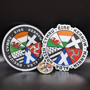May include: Two round, white-bordered patches with a white cross in the center and a circle of flags around the cross. The flags are from Ireland, Wales, Brittany, Scotland, and the Isle of Man. The text around the outside of the patches reads "ÉIRE, KERNOW, MANNIN, ALBA, BREIZH, CYMRU". A smaller, gold-colored patch with the same design is in the center of the image.