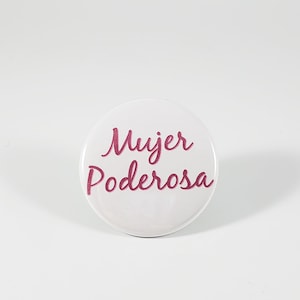 May include: White round button with the text "Mujer Poderosa" in pink cursive lettering.