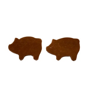 May include: Two brown pig-shaped cookie cutters, one facing left and one facing right.