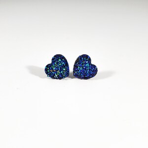 K&ouml;nnte beinhalten: Ein Paar blaue herzf&ouml;rmige Ohrringe mit Glitzer.