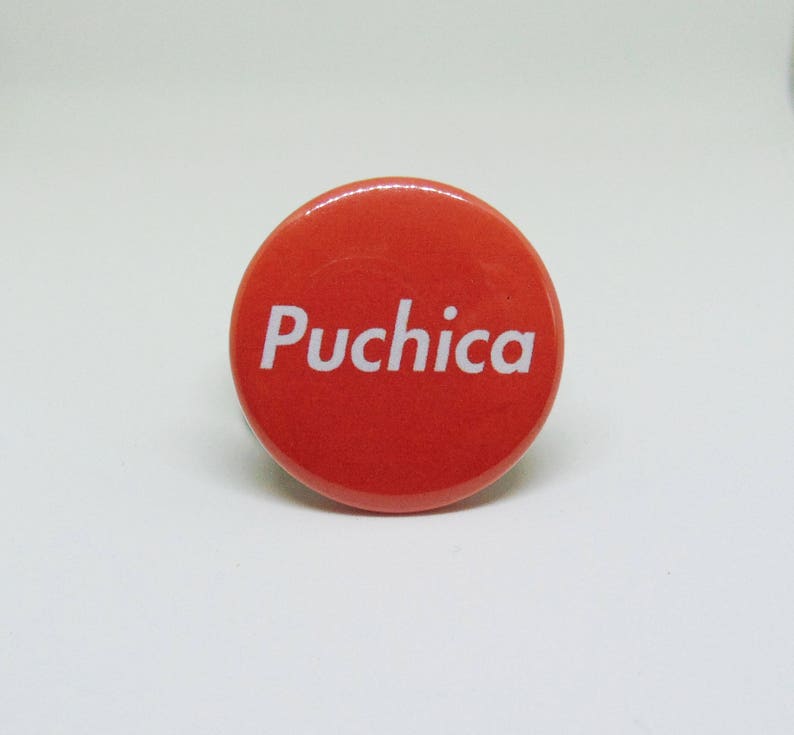 May include: A red round button with the word "Puchica" printed in white.