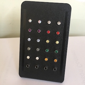 May include: A black display stand with 20 small round rhinestones in various colors, including clear, red, green, purple, and black.