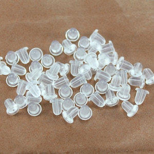 Peut inclure: Un tas de dos d'oreille en plastique transparent. Les dos sont petits et ronds, avec un petit trou au centre. Ils sont conçus pour être utilisés avec des boucles d'oreilles à clous.
