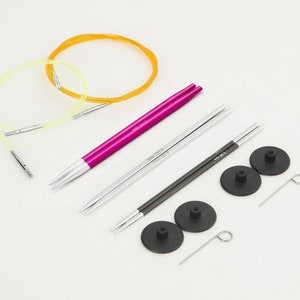 May include: A set of interchangeable knitting needles. The set includes two pairs of needles, one pair of circular needles, and three cable connectors. The needles are made of metal and have a silver finish. The circular needles are yellow and green. The cable connectors are black.