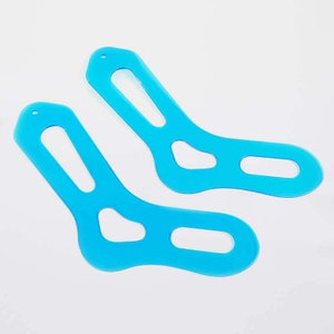 May include: Two light blue plastic sock shaping templates. The templates are shaped like socks with cutouts for the heel, toe, and ankle.