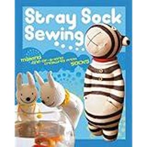 May include: The cover of a book, "Stray Sock Sewing", displays sock creatures. A tall, striped sock figure and two white sock bunnies are shown. The text reads "missing one-of-a-kind creatures from socks".