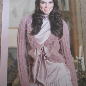 May include: A Patons knitting pattern showing a woman in a mauve knitted bolero with a bow. The pattern is for the "Orient DK" style, to fit sizes 81-107cm.