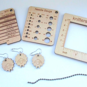 May include: A selection of wooden knitting tools, including a needle gauge, a gauge ruler, and a square ruler with inch and cm measurements. Also included are three sheep-shaped stitch markers and a metal chain.
