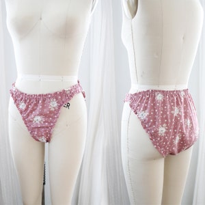 Op de afbeelding: Roze ondergoed met een bloemenprint en een gerimpelde rand. Het ondergoed is op een wit mannequin.