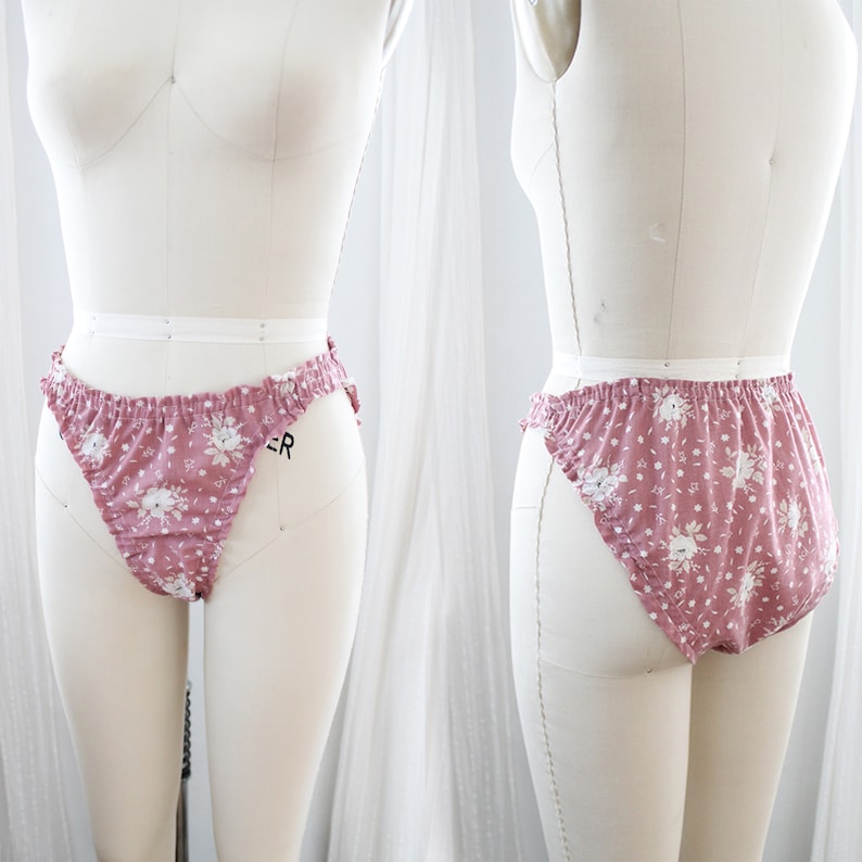 Op de afbeelding: Roze ondergoed met een bloemenprint en een gerimpelde rand. Het ondergoed is op een wit mannequin.