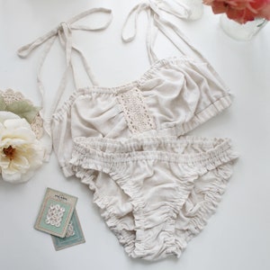 Op de afbeelding: Een witte lingerie set met een kanten randje op de top en een gerimpelde onderkant.