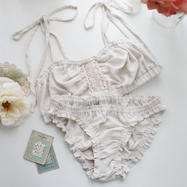Op de afbeelding: Een witte lingerie set met een kanten randje op de top en een gerimpelde onderkant.