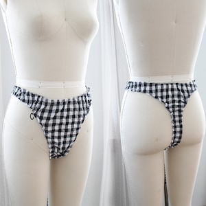 Op de afbeelding: Zwart-wit geruite ondergoed met een gerimpelde tailleband. Het ondergoed wordt getoond op een wit naaipop.