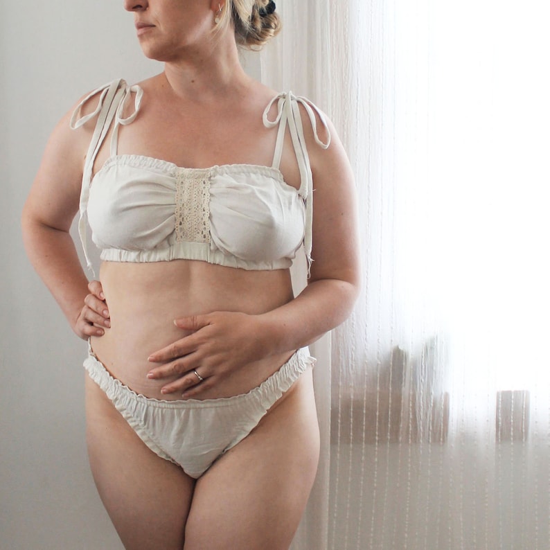 Op de afbeelding: Witte lingerie set met kant, bestaande uit een bandeau top en een geruit onderstuk.