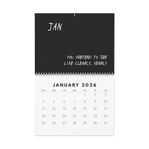 Peut inclure: Un calendrier mural noir et blanc pour janvier 2026. La partie supérieure présente le mot "JAN" en blanc, dans une police manuscrite, au-dessus de la citation "YOU PRETEND TO SEE LIFE CLEARLY, YEARLY". La grille du calendrier est blanche avec des chiffres noirs.