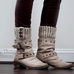 May include: A pair of beige crochet boot cuffs with brown buttons worn over tan ankle boots with metal studs.