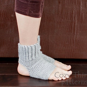May include: Gray crocheted foot warmers with an open heel and toe. The foot warmers are shown on a person's feet.